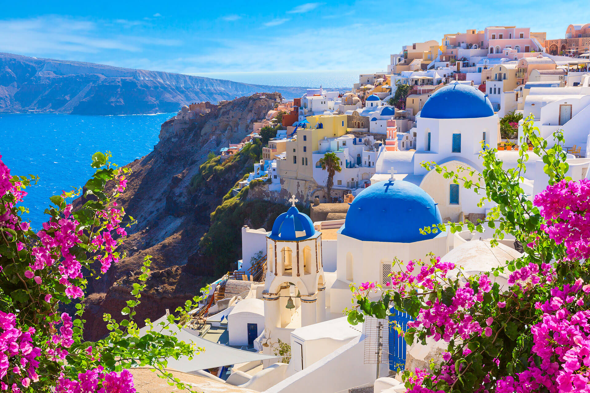 The stunning blue sea and bright white houses and churches with blue rooftops that make the Aegean Island of Santorini in Greece famous, and that can be toured on a vacation with Sky Bird Travel & Tours Sky Vacations.