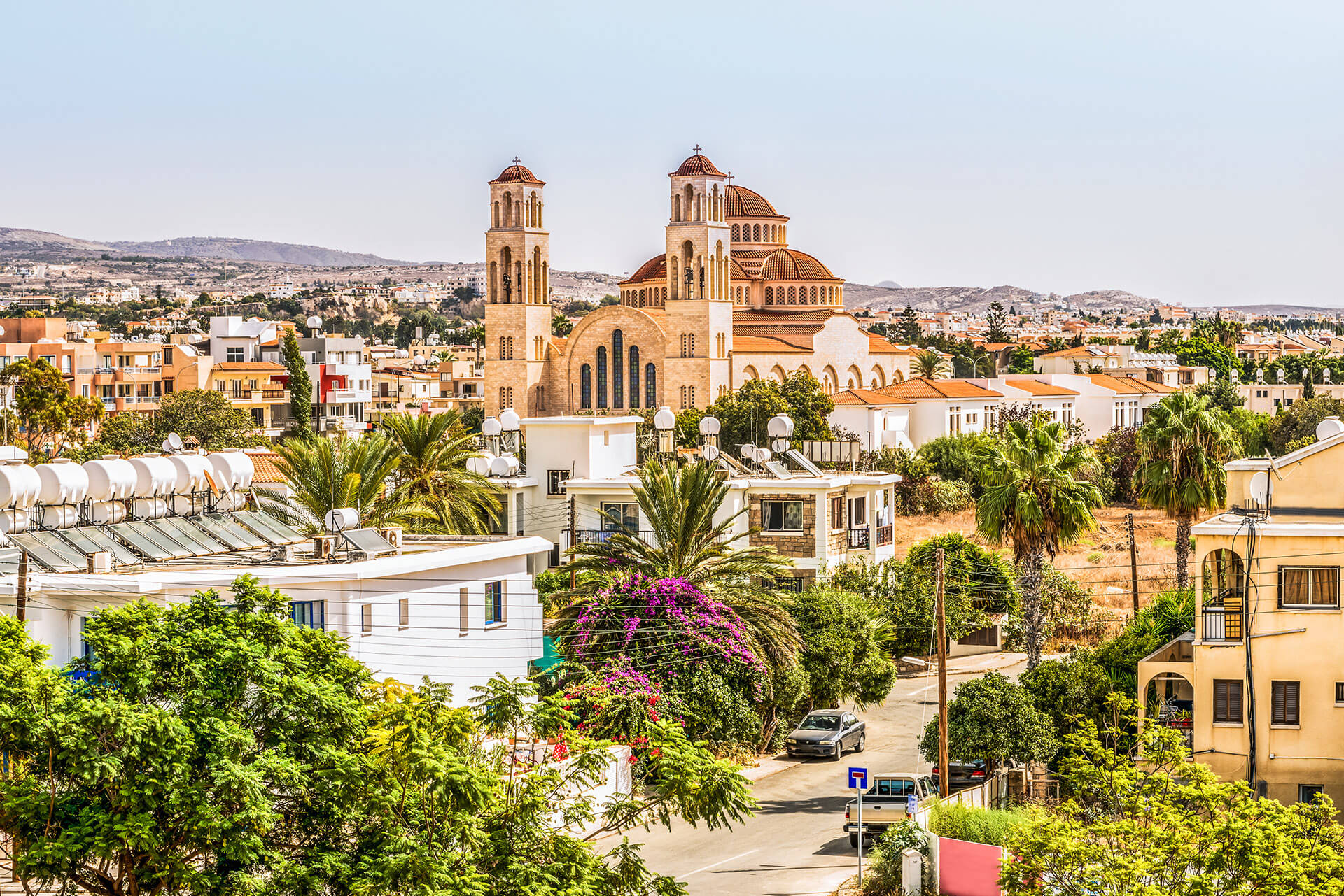 Paphos, the ancient city with old sandstone buildings, green trees, and a church with beautiful architecture, is from a city walking tour with Sky Bird Travel & Tours Sky Vacations luxury customized vacation package to Cyprus, Greece.