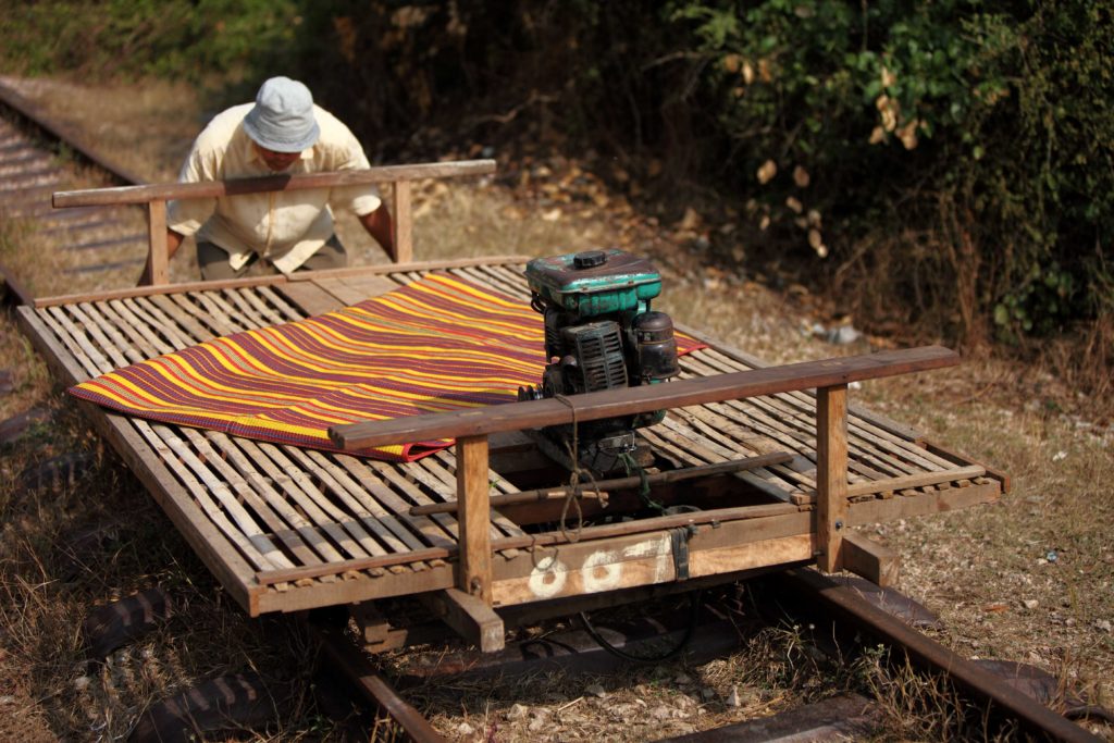 A travel photograph of a man operating a bamboo train in Battambang, Cambodia. This is an exciting tour for travel agents to book through Sky Bird Travel & Tours.