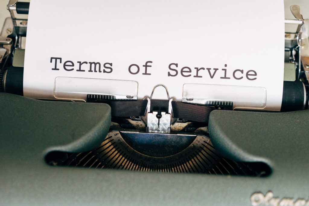 A closeup view of an old typewriter, with paper in the machine and ink typed out saying "terms of service." This describes the misconception of airline consolidators and travel agents like Jaya Travel & Tours.