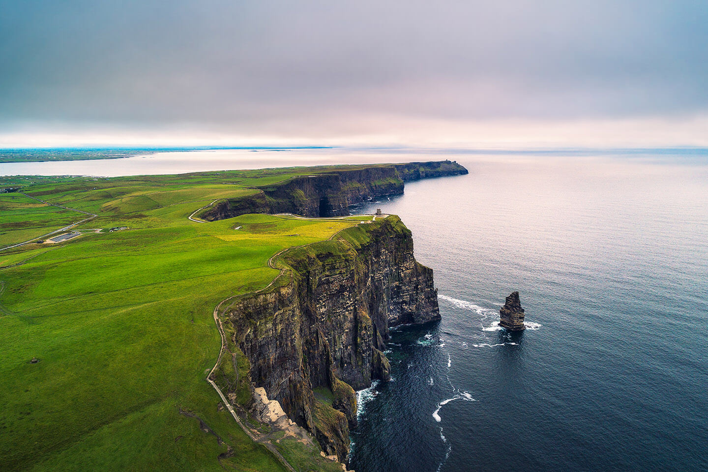 The stunning vast blue ocean on one side of the photo, and the stunning vast green land on the other side, with the cliffs of moher in Ireland dividing the two.