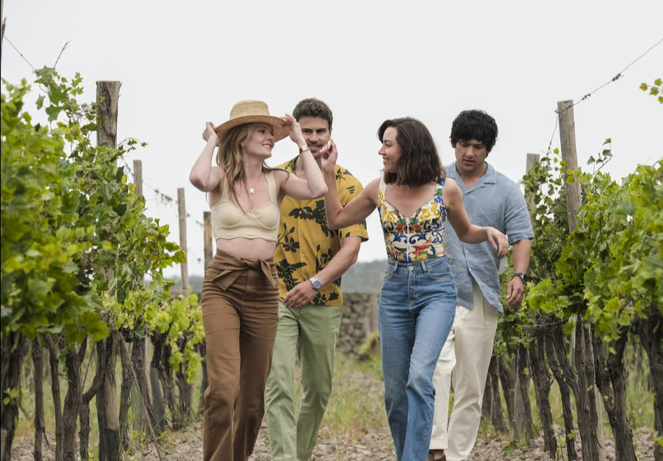 A still from the HBO Max TV show "The White Lotus" featuring Harper (Aubrey Plaza), Daphne (Meghann Fahy), Cameron (Theo James), and Ethan (Will Sharpe) walking through a vineyard in Italy. This image is featured in Sky Bird Travel & Tours blog article" On Location: The White Lotus," which explores the real-life filming locations of the white lotus season 1 and season 2.
