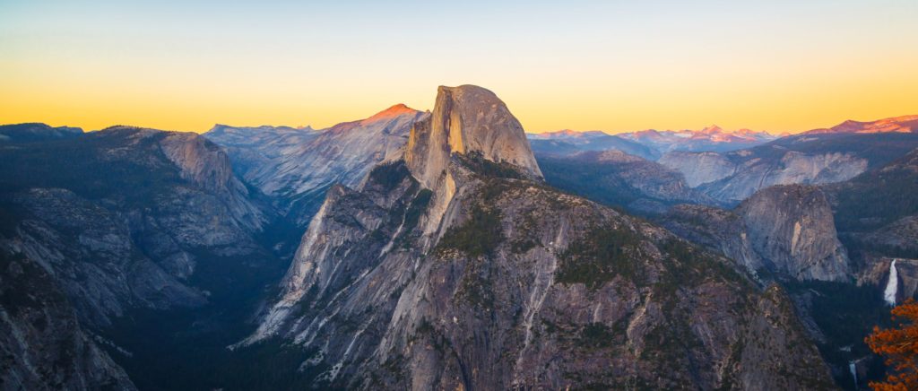 The legendary Half Dome glacier juts directly skyward from out of the mountain at Yosemite National Park in California and is offset by a striking sunset. This is a top 10 national park to travel in 2023, as declared by Sky Bird in their travel blog.