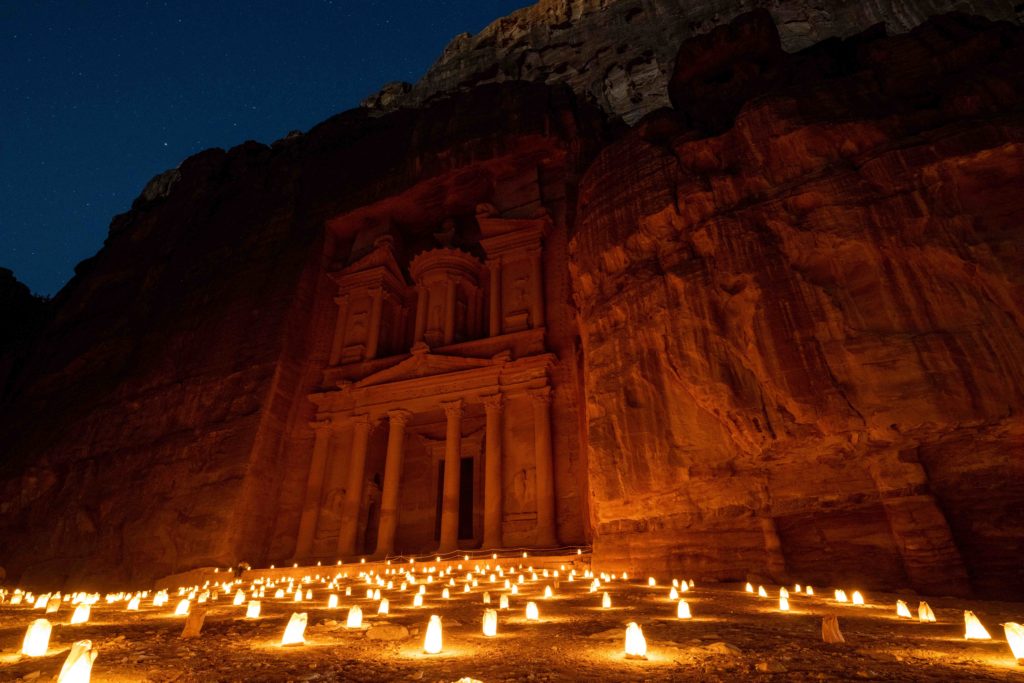 A beautiful shot of Petra under the stars at night with candles lit up around the red stone rock carvings, which is one of most beautiful things to do in the Middle East. This image is featured in the Sky Bird Travel & Tours tour guide blog article, "Top 10 Destination: Jordan," which lists the best things to do in Jordan!