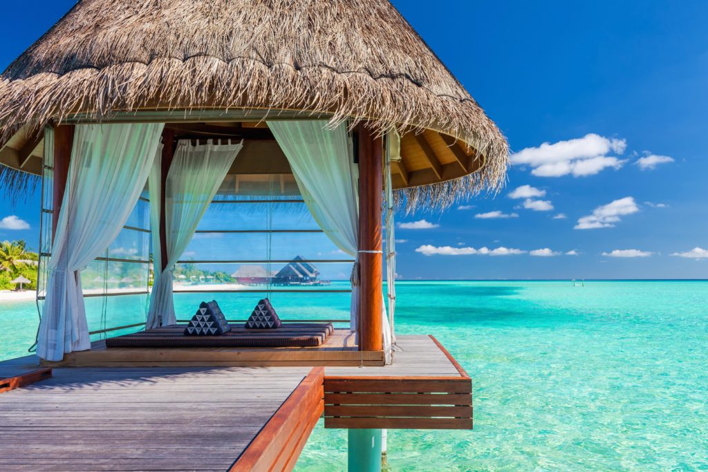 A beautiful hut in the Maldives, where married couples on a romantic vacation can have a couples massage over the water in a tropical bungalow. This image is featured in the Sky Bird Travel & Tours blog, "Best Destinations for Honeymooners," which shows travel agents the most romantic locations for honeymoon!