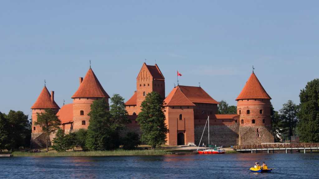 A landscape shot of the Trakai Island castle in Lithuania, which is an old medieval waterfront castle protected by old fortifications. This image is featured in the Sky Bird Travel & Tours blog post, "Top 10 Destination: The Baltics," which describes the best things to do while on vacation in the Baltic States.