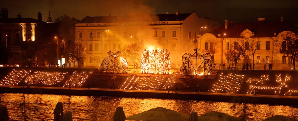 A large effigy burns in a public street square near a river to celebrate the autumn equinox festival in Vilnius, Lithuania. This image is featured in the Sky Bird Travel & Tours blog, "The Autumn Equinox," which describes the best places to view the fall equinox and how the festival started.