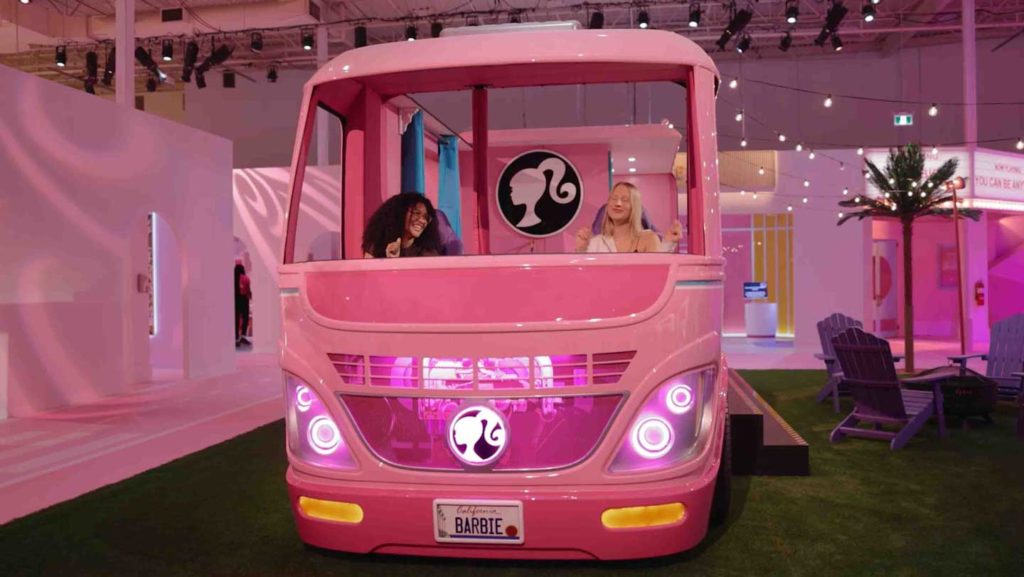 Featured in On Location: Barbie by Sky Bird Travel & Tours, this image shows two young girls stepping inside the life-sized version of the Barbie Dream Camper at World of Barbie in LA!