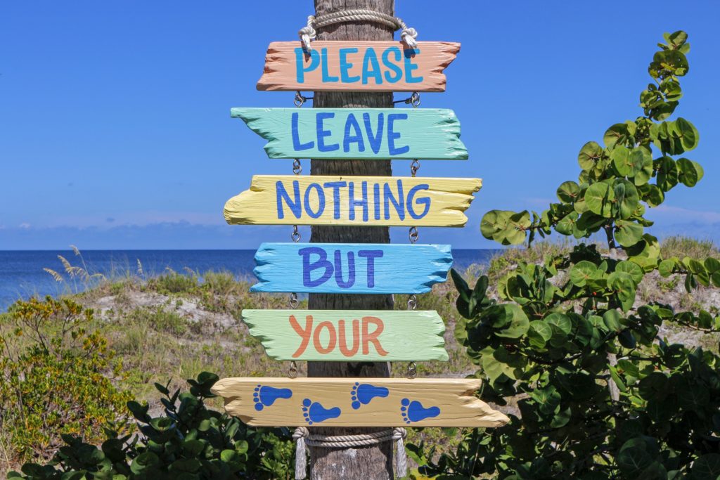 Featured in the blog "How To Celebrate World Tourism Day" by Sky Bird Travel & Tours, this image shows a sign at the beach which tells people to not litter.