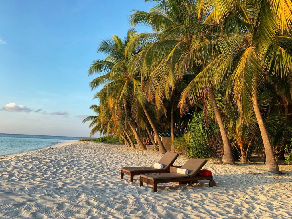 Featured in the top luxury retreats of 2023 by sky bird travel & tours, this image shows two chairs on a beach in the maldives