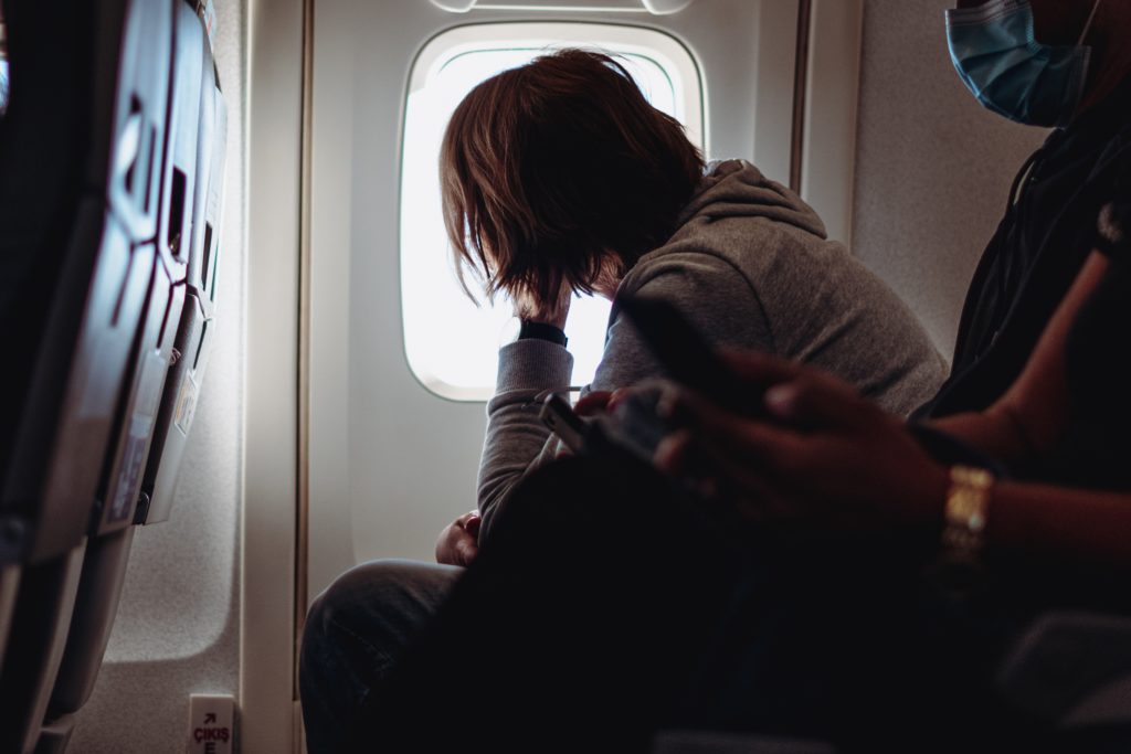 Featured in Understanding Flight Classes by Sky Bird Travel & Tours, this featured image shows a person looking out the window of a plane from their seat.