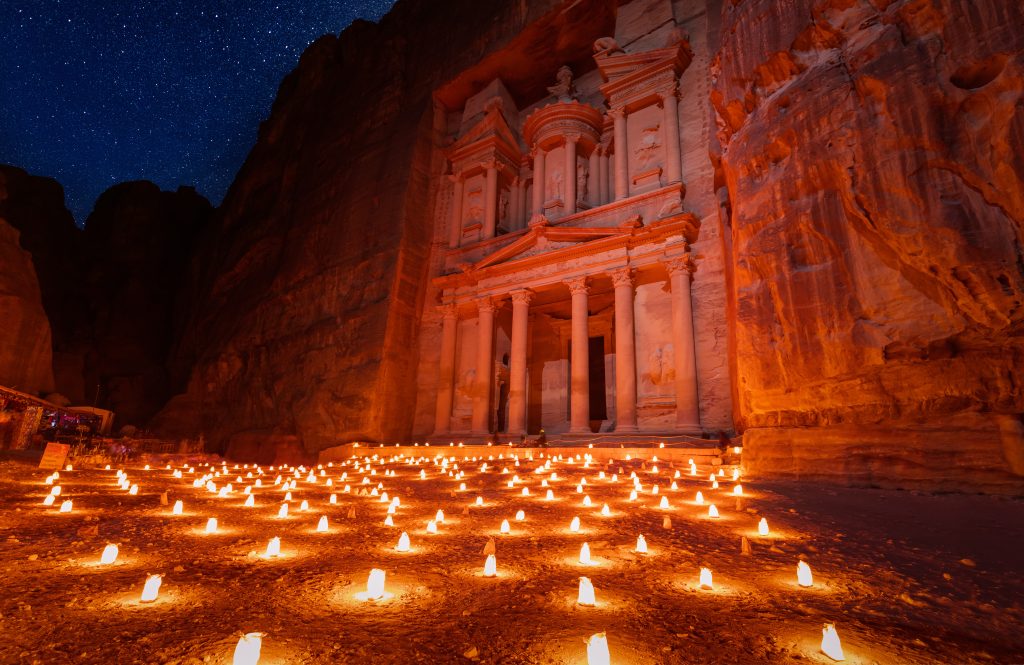 Featured in the blog Trending Travel Experiences of 2025 by Sky Bird Travel & Tours, this image shows the rock carvings of Petra, Jordan at night illuminated by lanterns.