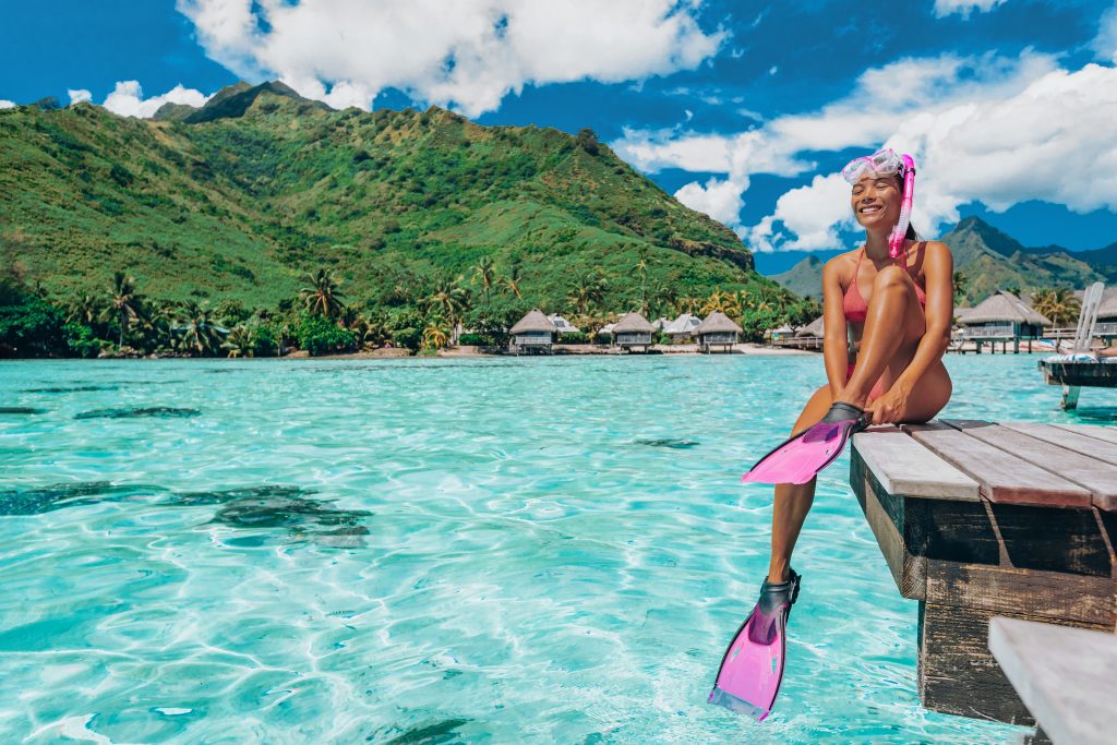 Featured in the blog Trending Travel Experiences of 2025 by Sky Bird Travel & Tours, this image shows a Featured in the blog Trending Travel Experiences of 2025 by Sky Bird Travel & Tours, this image shows a woman in diving flippers sitting on a boat.
